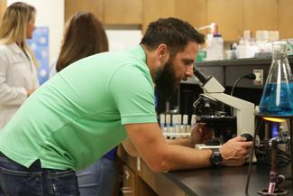 男学生通过显微镜观察